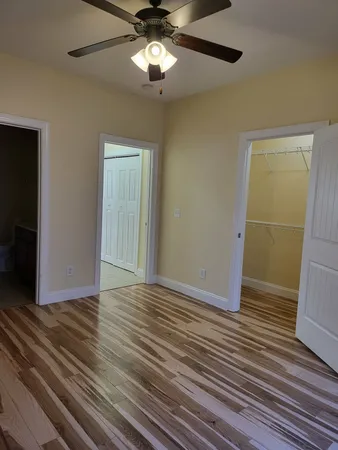 an empty room with wooden floor closet and windows