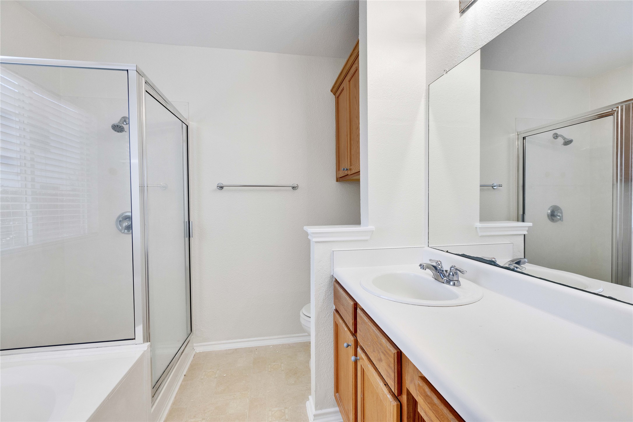 14418 Pebble Run Path Manor, TX 78653 - Photo 14 of 27 A well-appointed bathroom features a glass-enclosed shower, a vanity with a sink, and a large mirror.