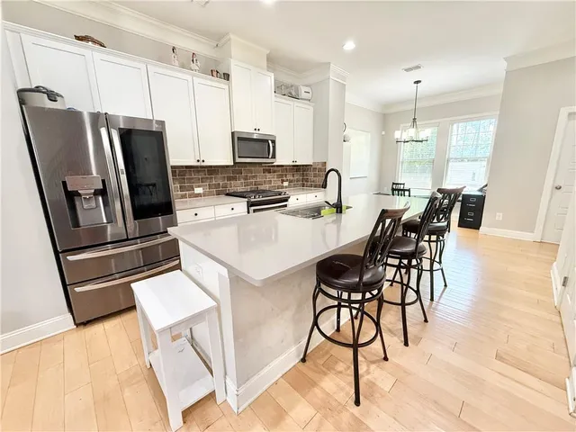 a kitchen with stainless steel appliances a stove a refrigerator a sink a dining table and chairs