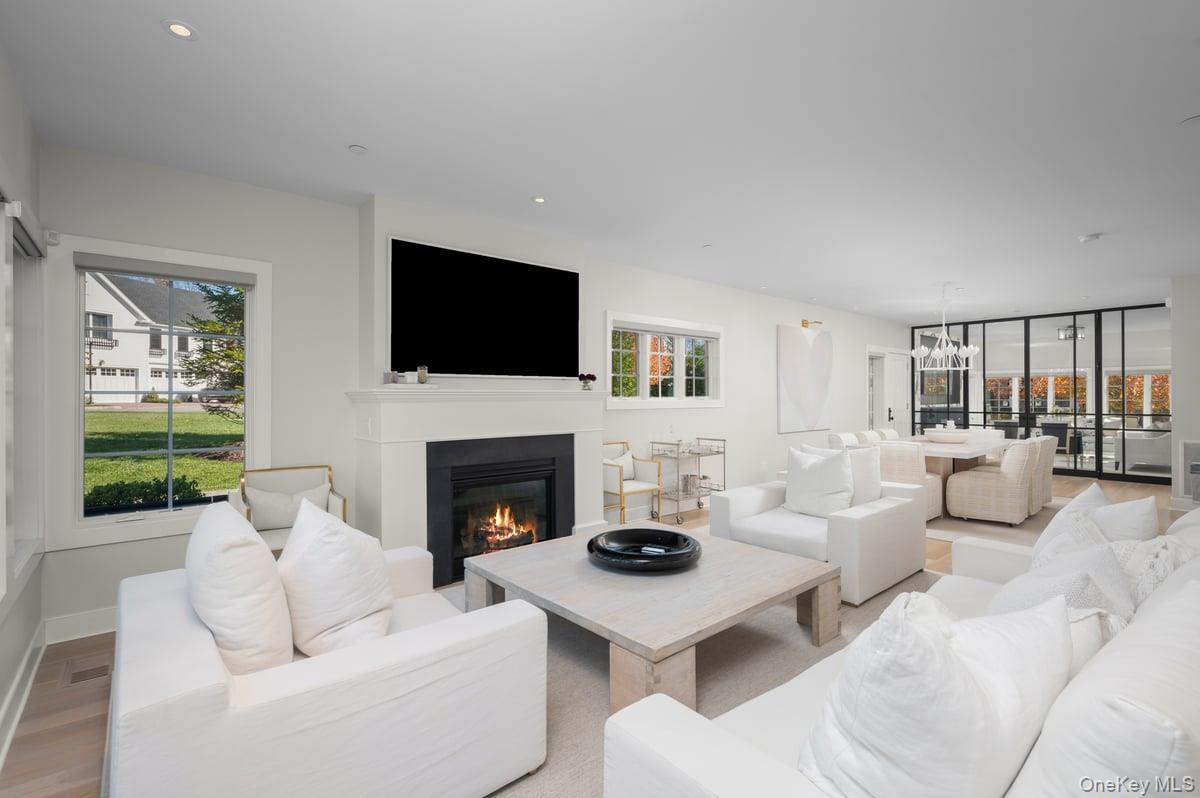 1 Primrose Lane Rye Brook, NY 10573 - Photo 4 of 42 Living area with a glass covered fireplace, a chandelier, wood finished floors, and recessed lighting