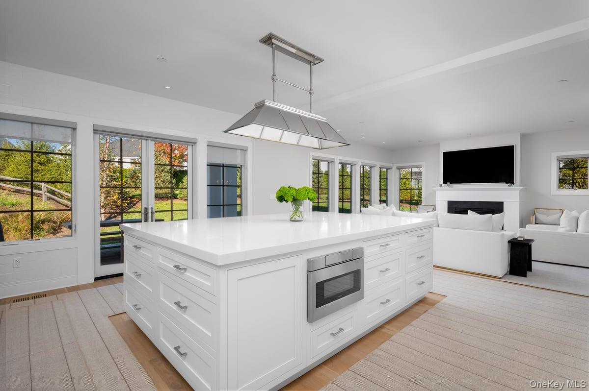 1 Primrose Lane Rye Brook, NY 10573 - Photo 42 of 42 Kitchen featuring white cabinetry, a kitchen island, light wood-style flooring, open floor plan, and stainless steel microwave