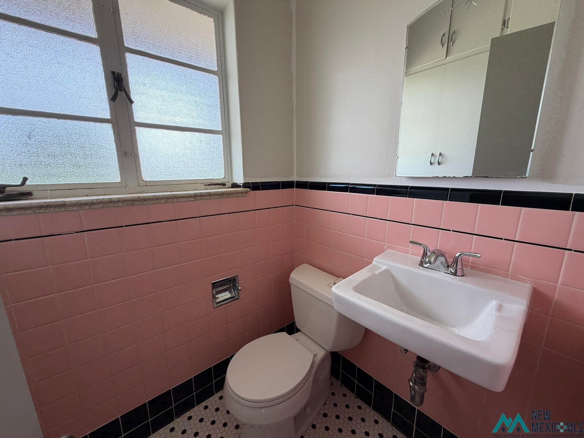 570 Curry Road North Clovis, NM 88101 - Photo 51 of 59 Bathroom featuring pink wall tiles with black trim, a white pedestal sink, and a white toilet