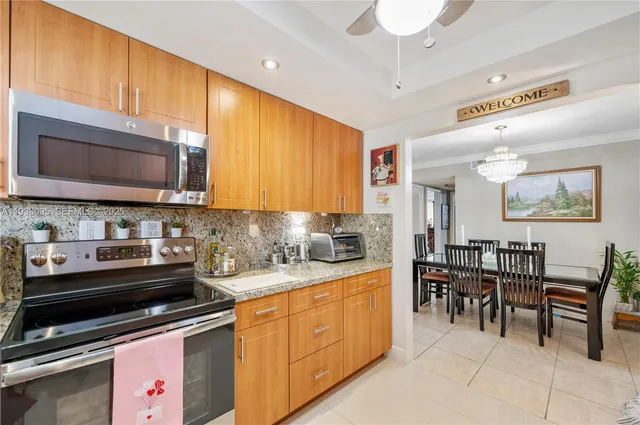 a kitchen with stainless steel appliances granite countertop wooden cabinets a stove a sink and a microwave