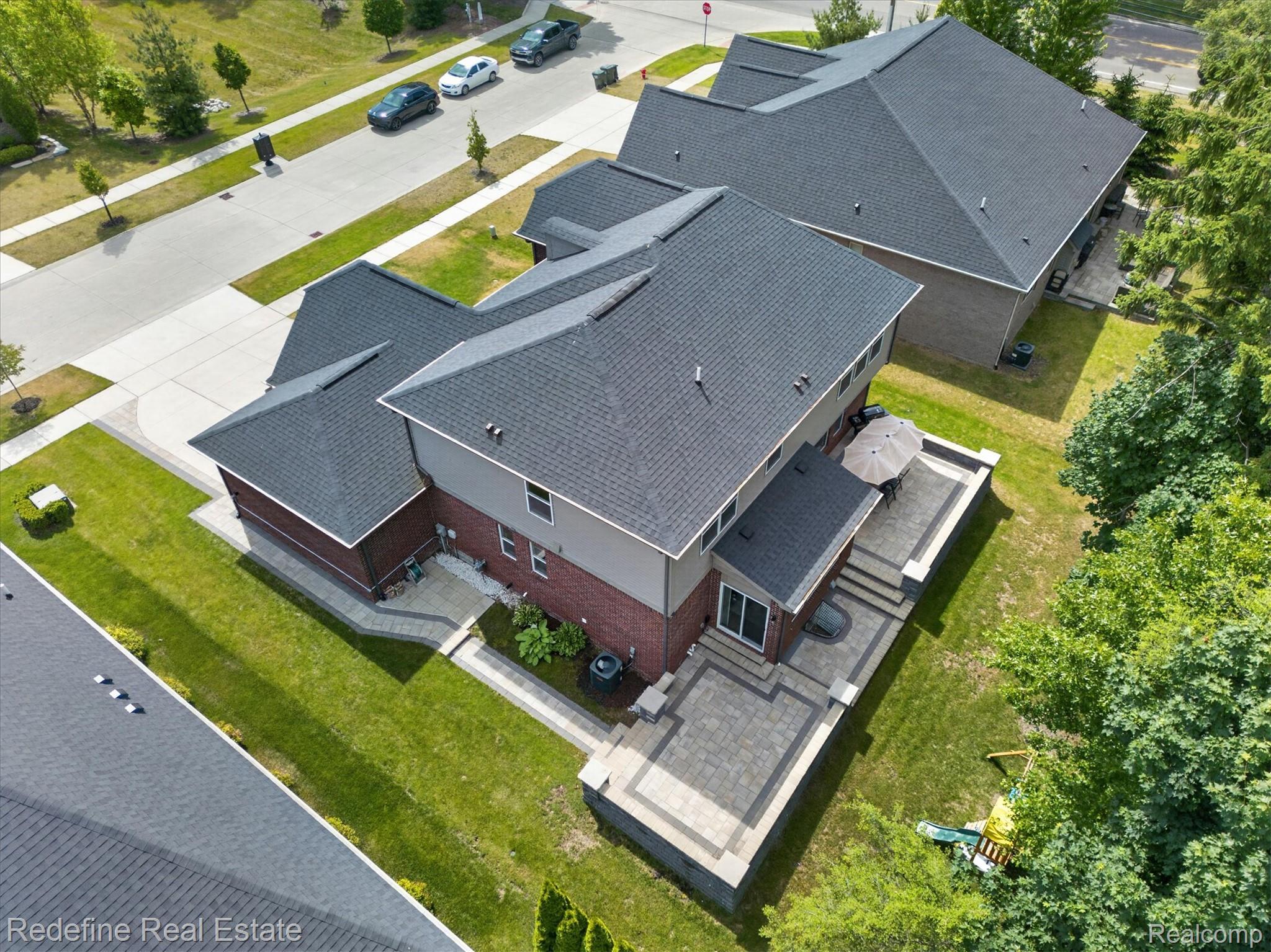 2976 Andlaur Drive Rochester, MI 48307 - Photo 51 of 60 Rear exterior featuring a multi-level paver patio, mature trees, and a well-maintained lawn