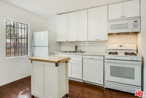 a kitchen with granite countertop white cabinets and white appliances