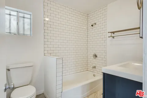 a bathroom with a bathtub shower sink vanity and toilet