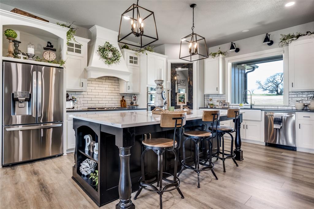 123 Proctor Lane Decatur, TX 76234 - Photo 7 of 25 a kitchen with granite countertop a table chairs stove refrigerator and cabinets