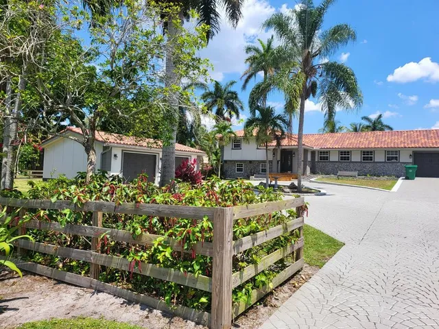 a front view of a house with a yard and potted plants