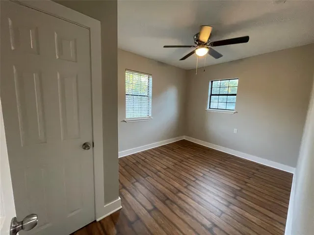 a view of an empty room with wooden floor and a window