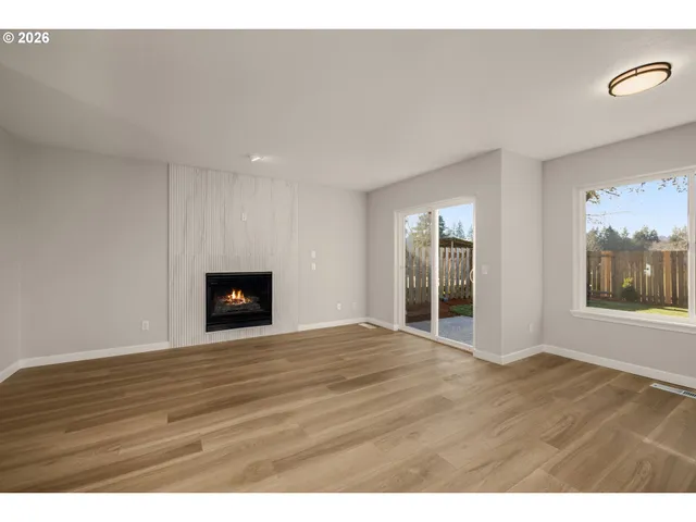 a view of an empty room with window and wooden floor