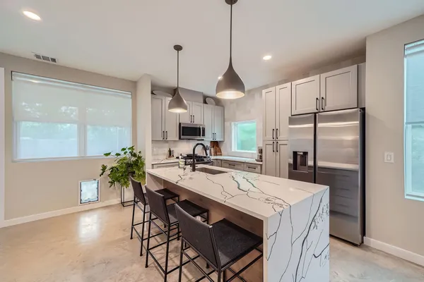a kitchen with granite countertop a table chairs stove and refrigerator