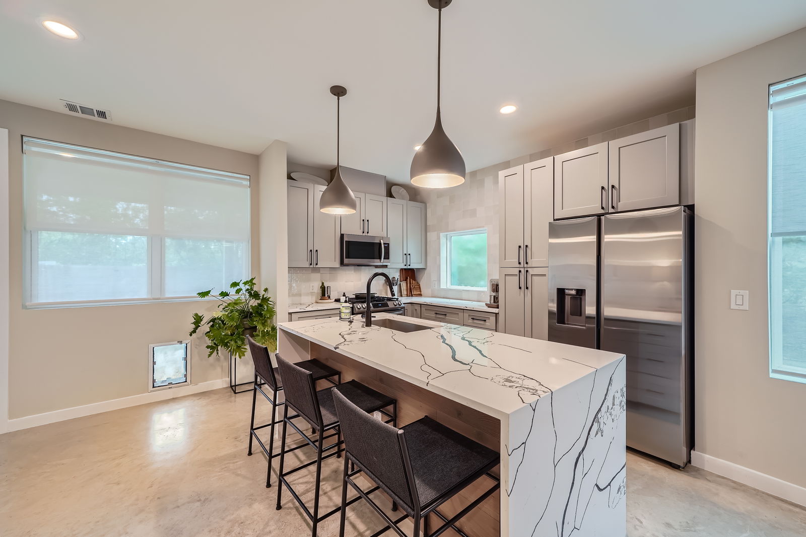 7507 Bethune Avenue, Unit B Austin, TX 78752 - Photo 3 of 23 Kitchen featuring a breakfast bar, appliances with stainless steel finishes, a sink, beautiful quartz counters, and tile backsplash. Space for a dining table.