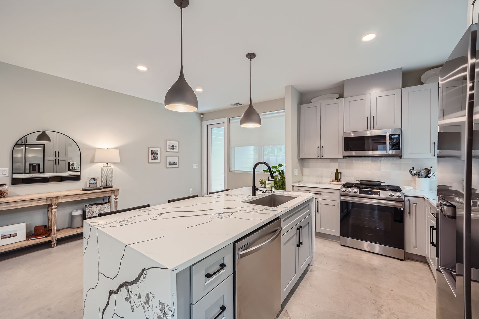 7507 Bethune Avenue, Unit B Austin, TX 78752 - Photo 4 of 23 Kitchen featuring tile backsplash, concrete floors, appliances with stainless steel finishes, a sink, and light cabinets