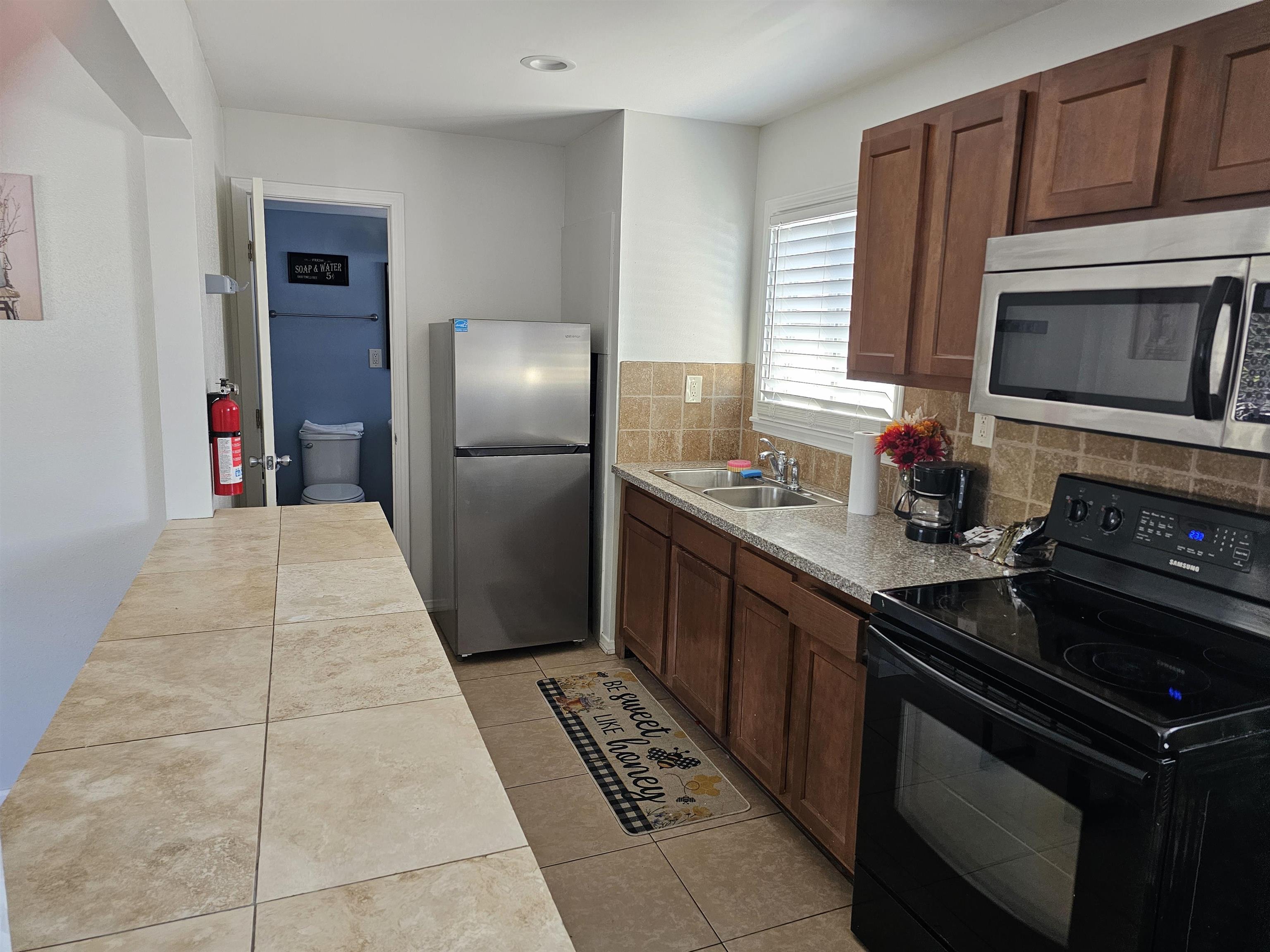 461 High Street Bishop, CA 93514 - Photo 6 of 10 Kitchen featuring wood-finish cabinetry, granite-style countertops, a stainless steel microwave, and a black electric range