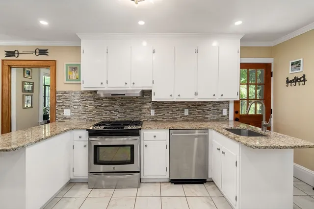 a kitchen with granite countertop white cabinets and white stainless steel appliances
