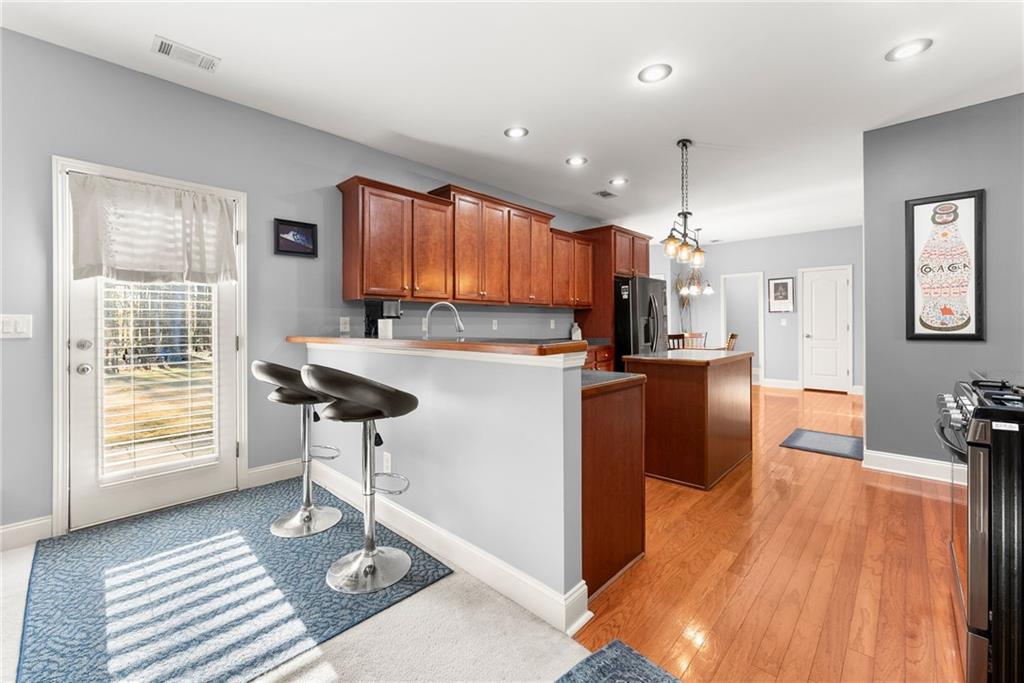 725 Larry Lane Winder, GA 30680 - Photo 18 of 62 a kitchen with stainless steel appliances kitchen island granite countertop a refrigerator a stove a sink dishwasher with a dining table and chairs with wooden floor