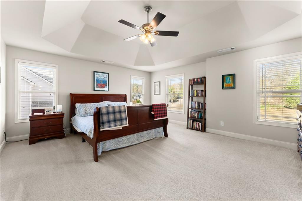 725 Larry Lane Winder, GA 30680 - Photo 27 of 62 a spacious bedroom with a bed and a chandelier