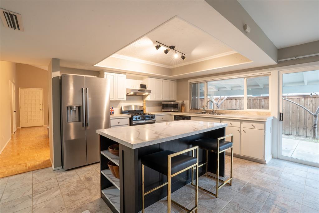 3124 Barton Road Carrollton, TX 75007 - Photo 21 of 36 a kitchen with kitchen island a table and refrigerator