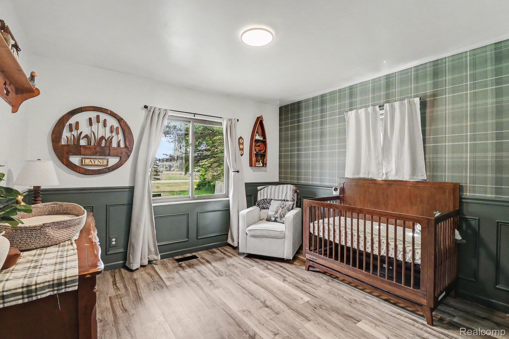 2905 German Road Columbiaville, MI 48421 - Photo 18 of 31 Room featuring wood-finish flooring, a plaid accent wall, and wainscoting