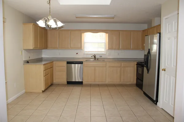 a kitchen with a cabinets a sink a window and stainless steel appliances