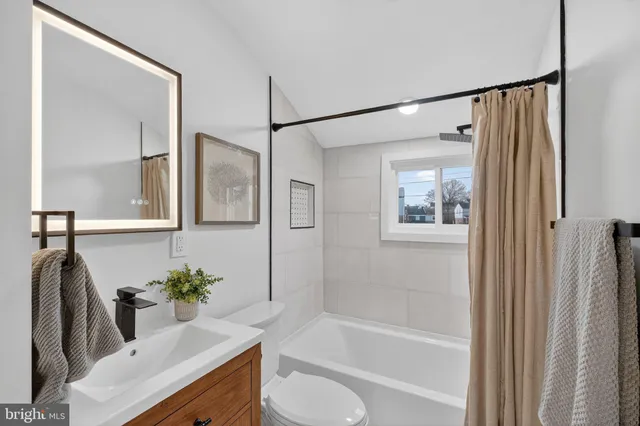 a bathroom with a granite countertop sink a mirror a bathtub and shower