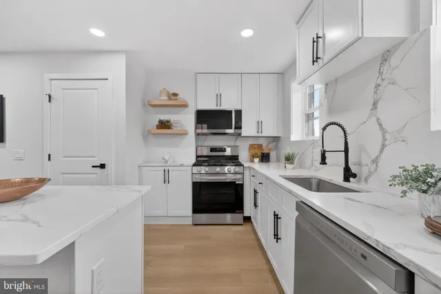 a kitchen with stainless steel appliances a stove sink and white cabinets