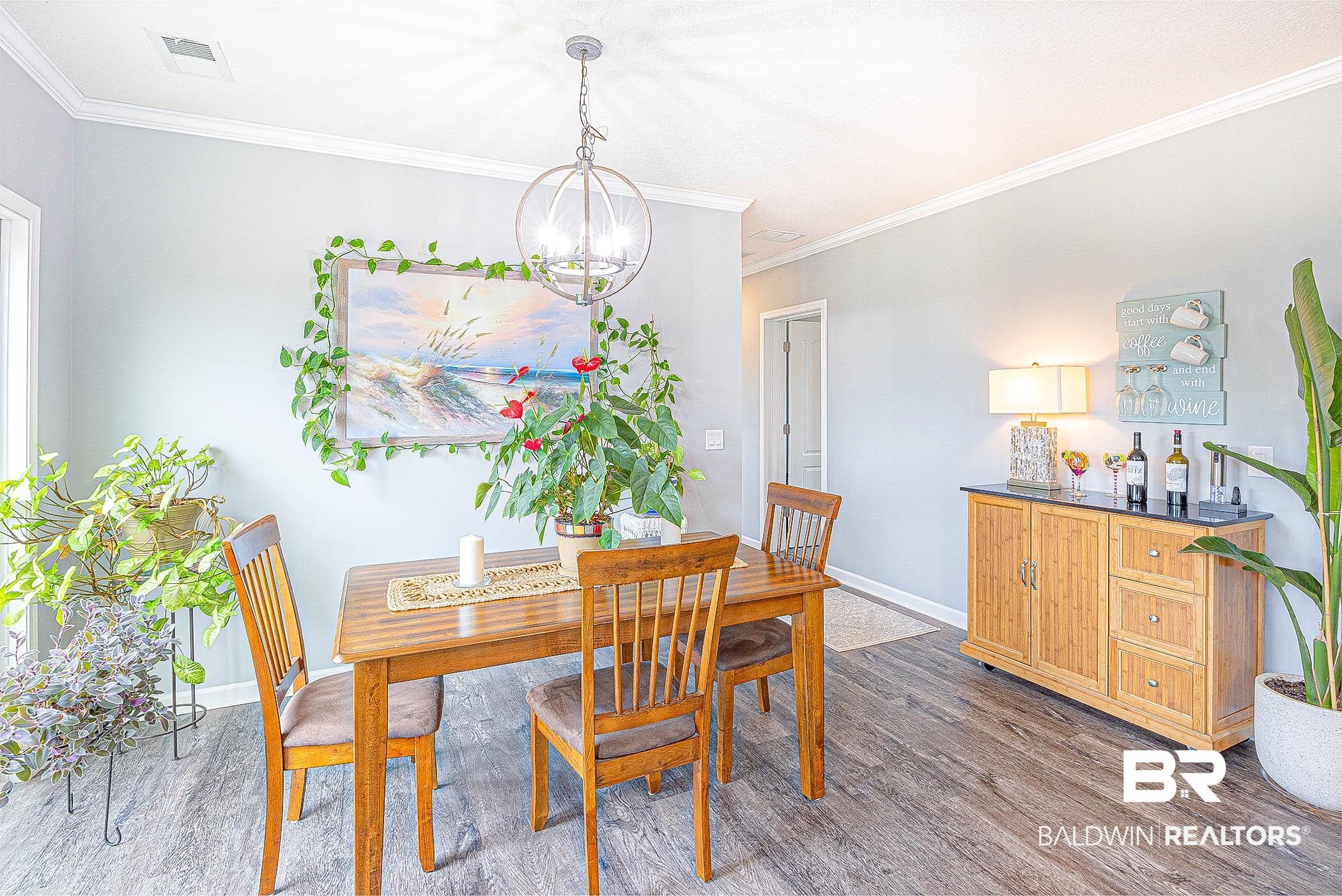 16000 John Bauer Road Summerdale, AL 36580 - Photo 15 of 34 Dining area with a notable chandelier, dark wood-type flooring, visible vents, baseboards, and crown molding