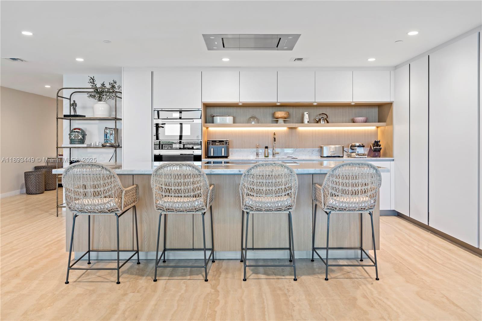 1135 103rd Street, Unit PH2 Bay Harbor Islands, FL 33154 - Photo 6 of 20 a kitchen with stainless steel appliances kitchen island granite countertop a table chairs and a refrigerator