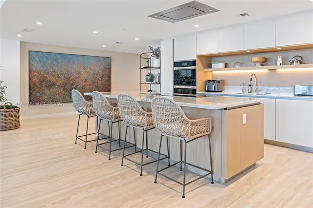 a kitchen with stainless steel appliances granite countertop a stove a sink a refrigerator and white cabinets with wooden floor