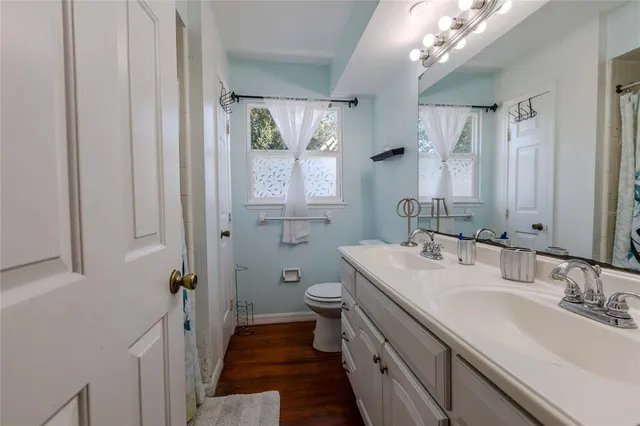 a bathroom with a granite countertop sink a toilet a mirror and shower