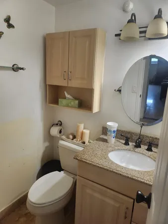 a bathroom with a granite countertop toilet sink and mirror
