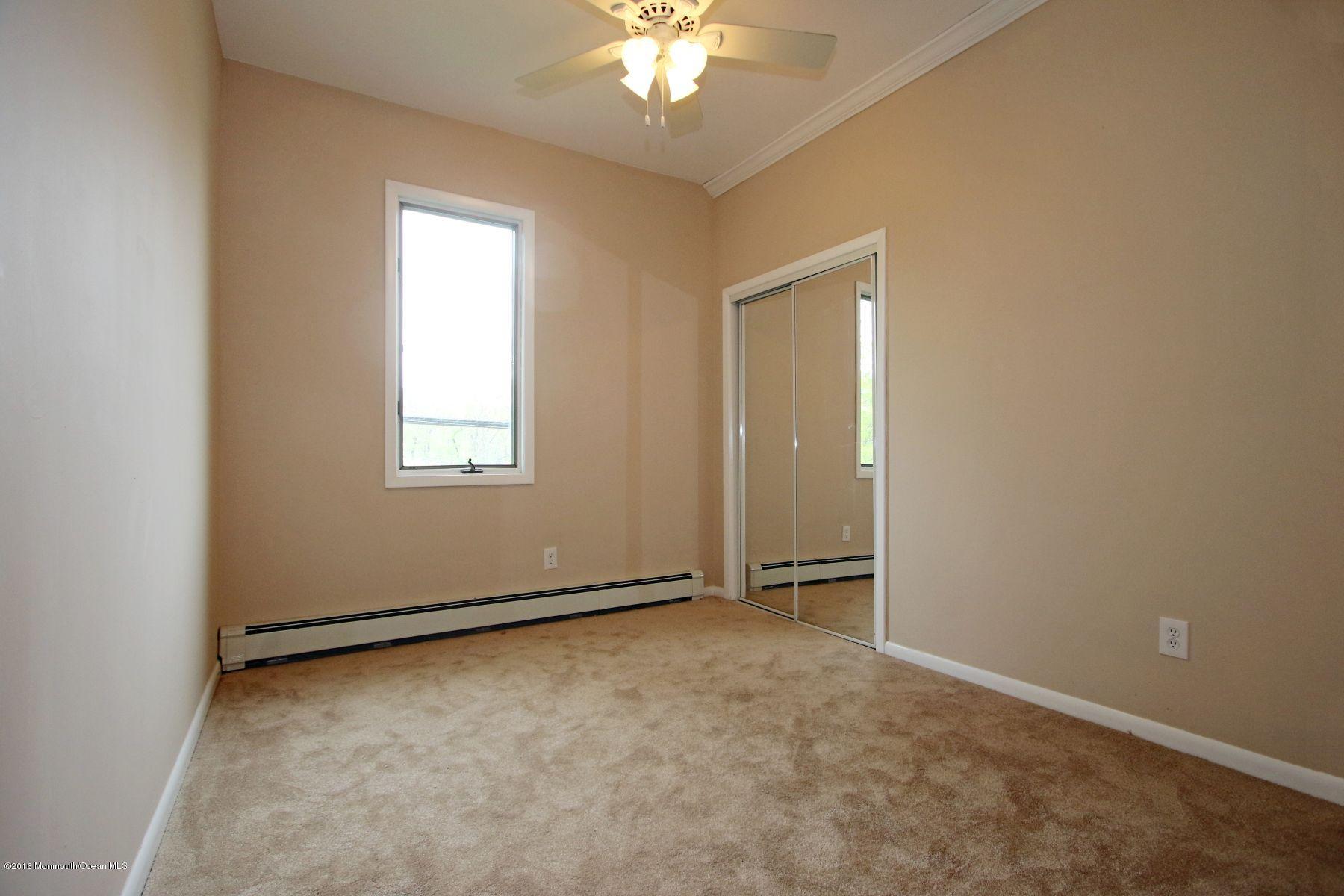 186 Pinebrook Road Tinton Falls, NJ 07724 - Photo 40 of 41 an empty room with a chandelier fan and windows