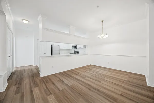 a view of kitchen and empty room with wooden floor