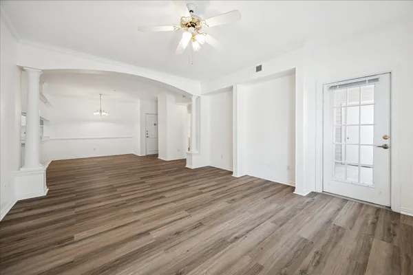 a view of empty room with wooden floor and ceiling fan