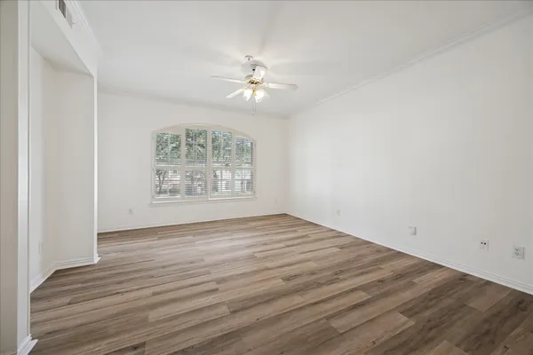 an empty room with wooden floor chandelier fan and windows