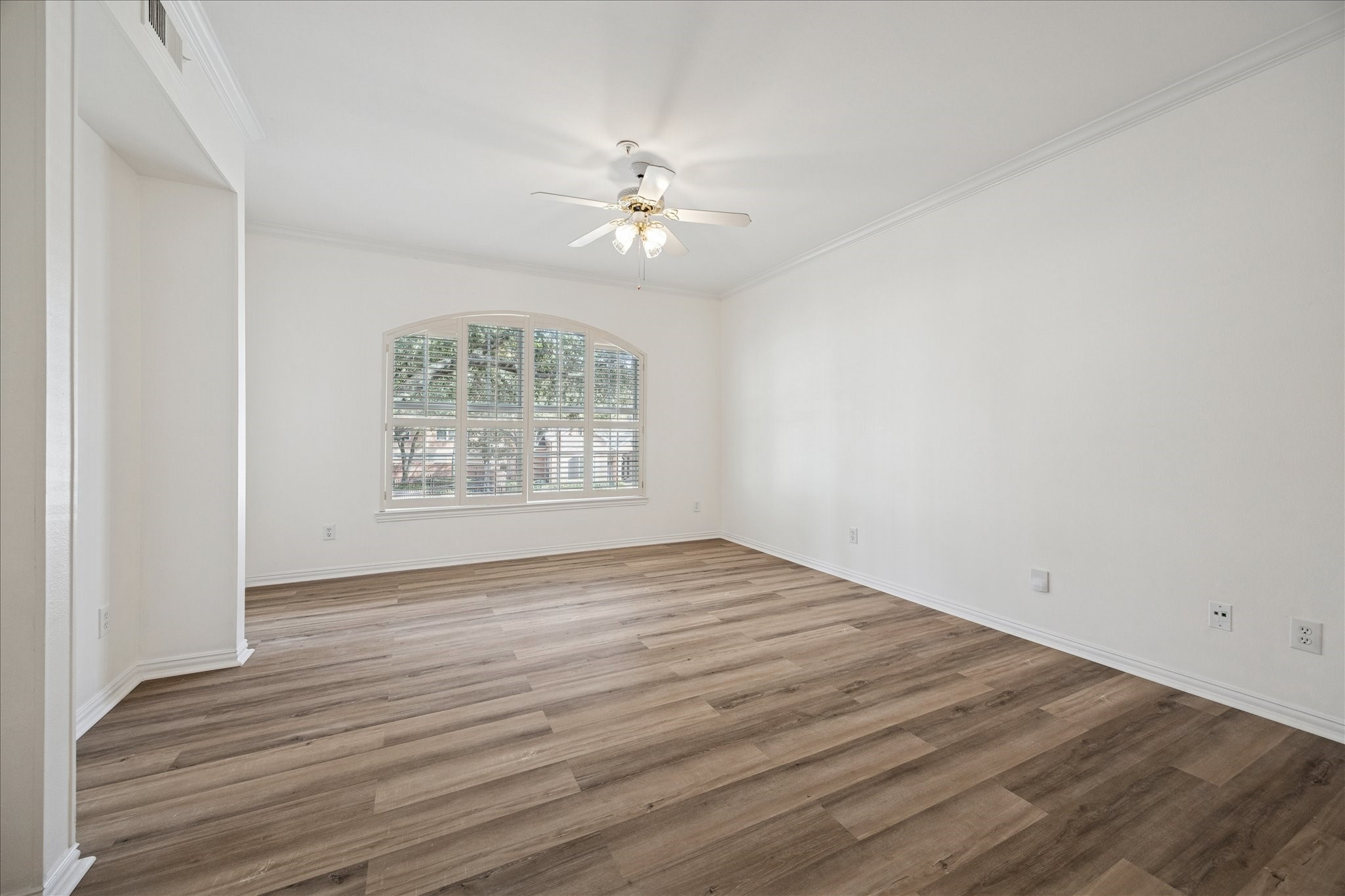 2111 Welch Street, Unit A103 Houston, TX 77019 - Photo 9 of 24 an empty room with wooden floor chandelier fan and windows
