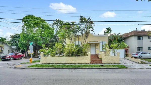 a front view of a house with a yard and potted plants