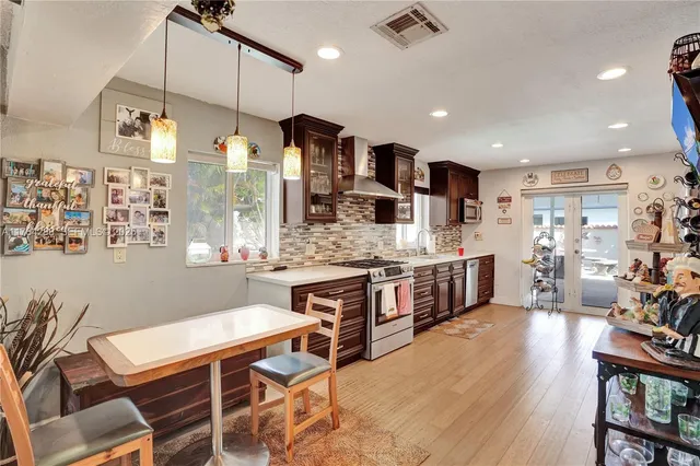 a kitchen with stainless steel appliances kitchen island granite countertop a table chairs and a refrigerator