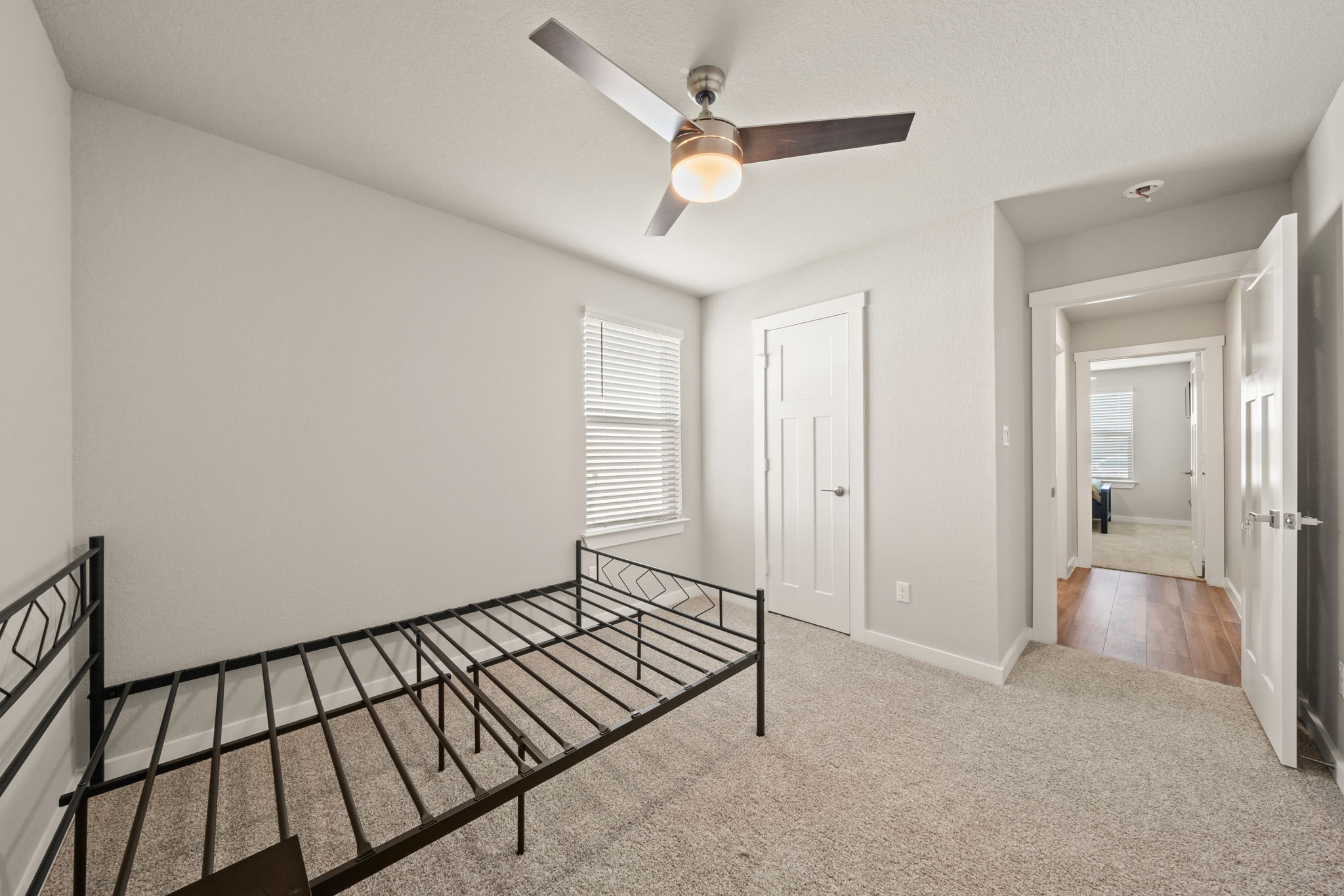 1117 Tipton Street Georgetown, TX 78633 - Photo 35 of 40 Bedroom featuring light gray wall paint, textured carpeting, a window with blinds, a modern ceiling fan, and a paneled white door