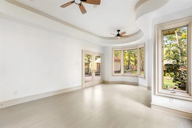 an empty room with windows and ceiling fan