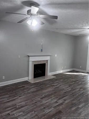 a view of an empty room with wooden floor fireplace and a window