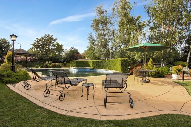 a view of a swimming pool with table and chairs under an umbrella