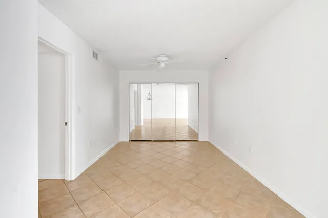 a view of an empty room with window and chandelier fan