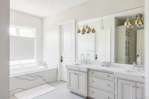 a bathroom with a granite countertop double vanity sink a mirror and a bathtub