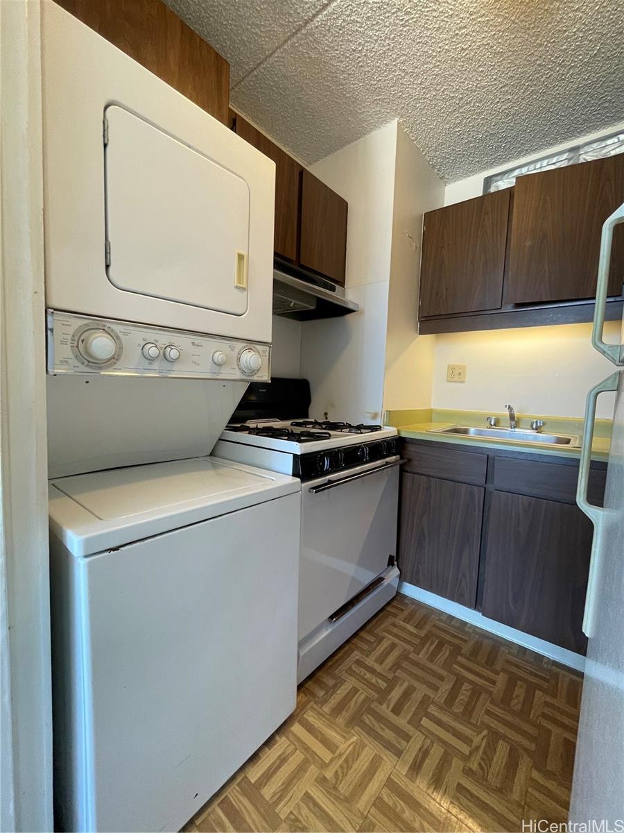 1624 Dole Street, Unit 804 Honolulu, HI 96822 - Photo 4 of 8 a kitchen with stainless steel appliances a stove a microwave and white cabinets