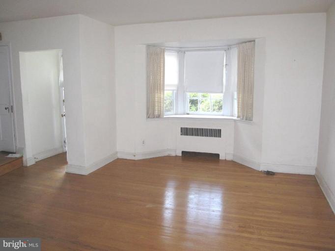 6431 Blenheim Road Baltimore, MD 21212 - Photo 5 of 12 an empty room with wooden floor and windows