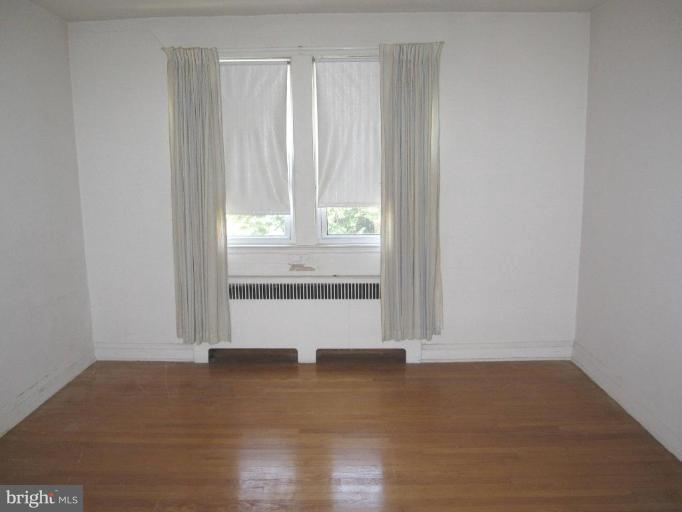 6431 Blenheim Road Baltimore, MD 21212 - Photo 9 of 12 an empty room with wooden floor and windows