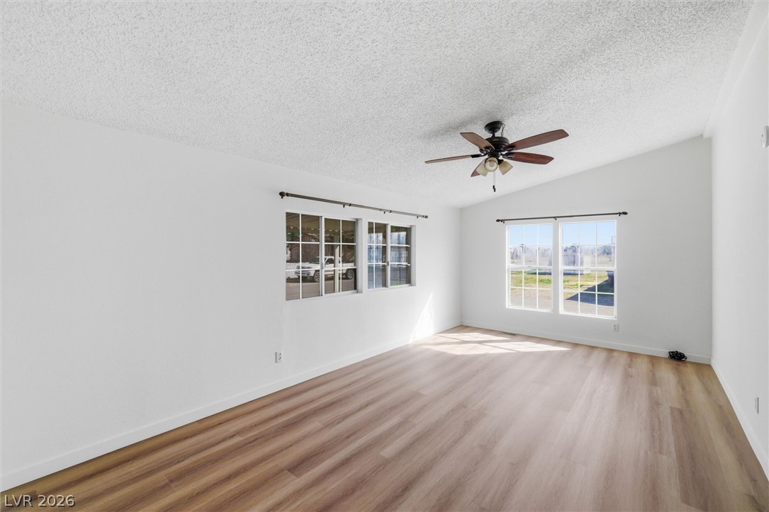 20 Rudy Road Pahrump, NV 89048 - Photo 8 of 32 Natural light streams across rich wood-look flooring under a vaulted ceiling.