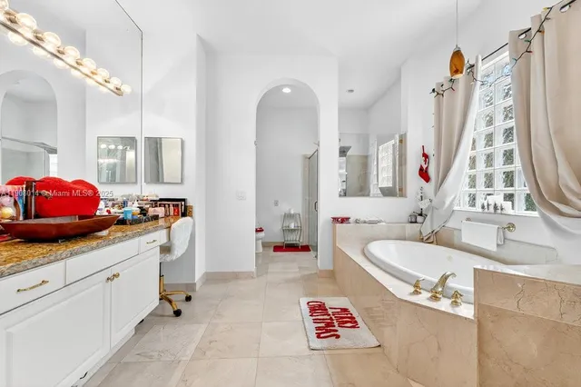 a spacious bathroom with a tub sink and mirror