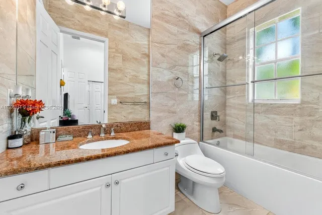 a bathroom with a granite countertop sink a toilet and shower